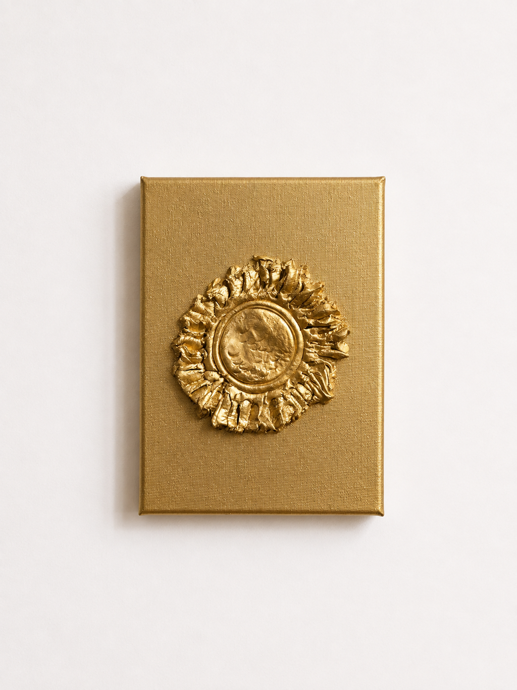 A square gold box with a raised circular sunburst medallion on the front, photographed against a plain white background.