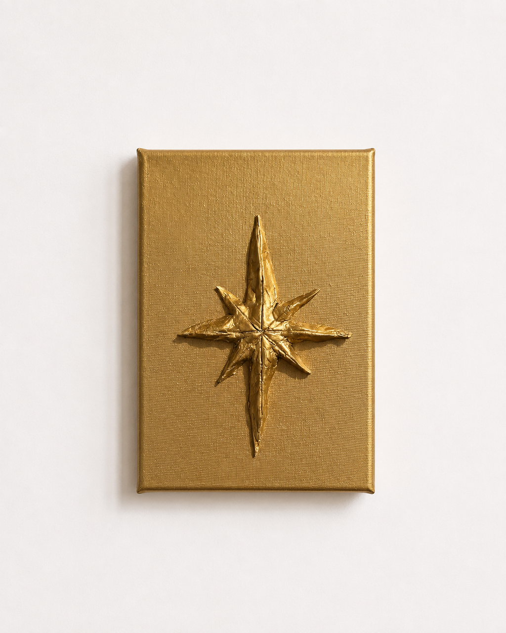 A square gold box with a raised metallic gold compass rose emblem on the front, photographed against a clean white background.