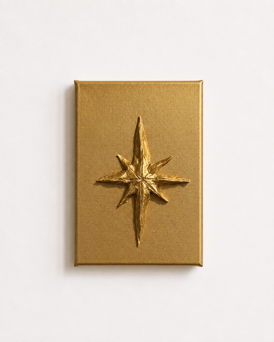 A square gold box with a raised metallic gold compass rose emblem on the front, photographed against a clean white background.