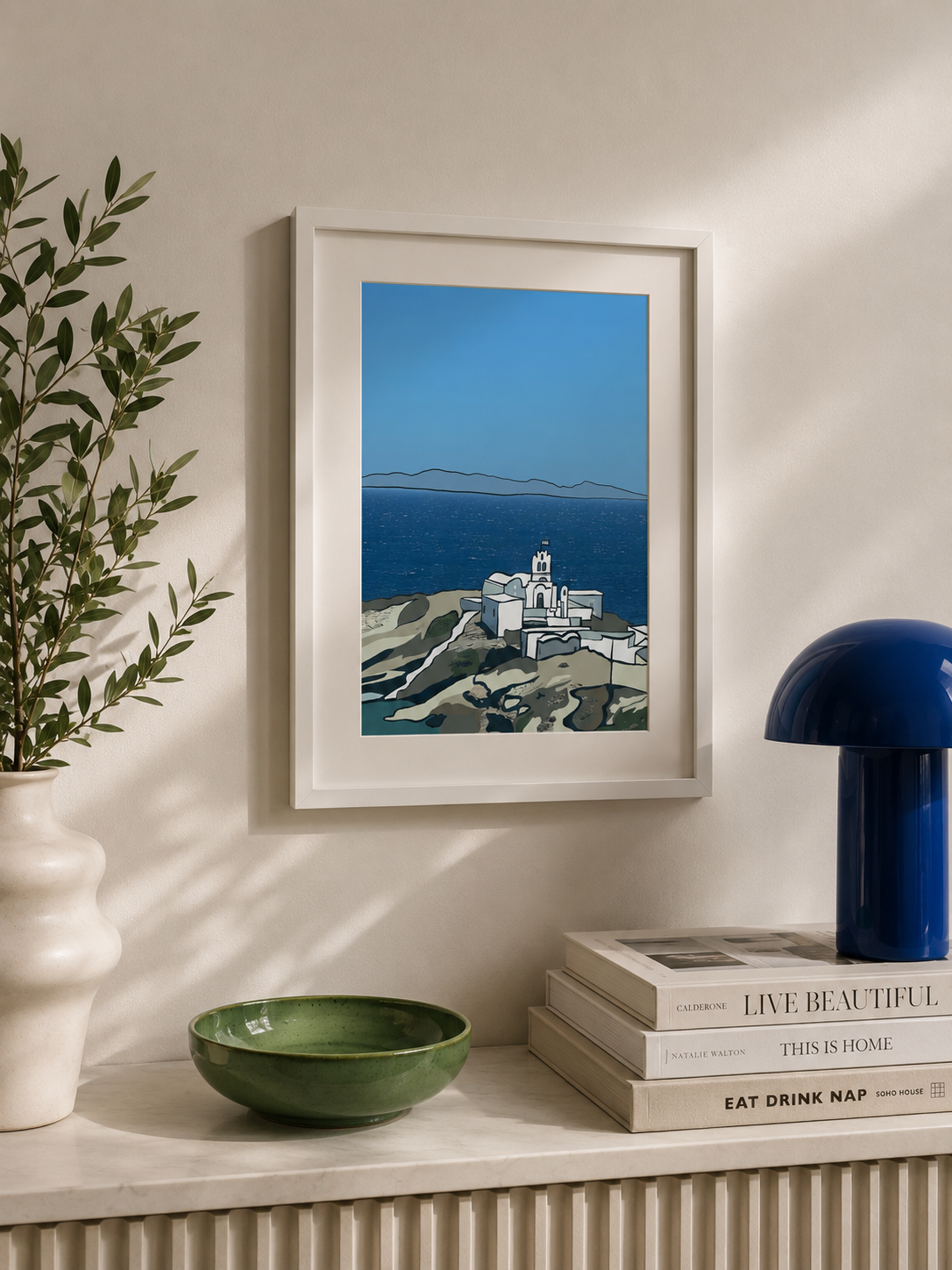 A3 Sifnos print framed on a wall styled with a plant and books