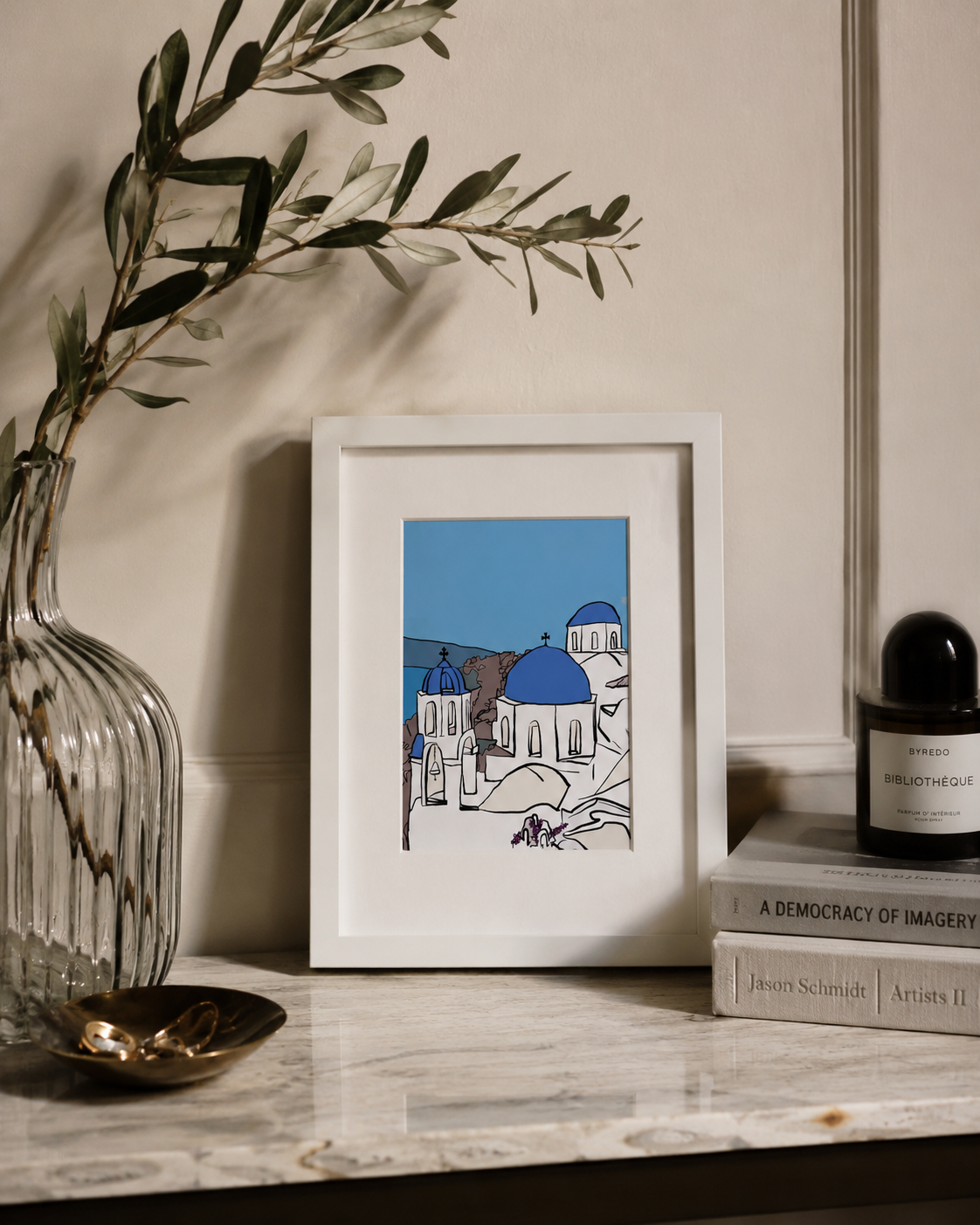 A5 Santorini print styled on a marble surface with a vase and books