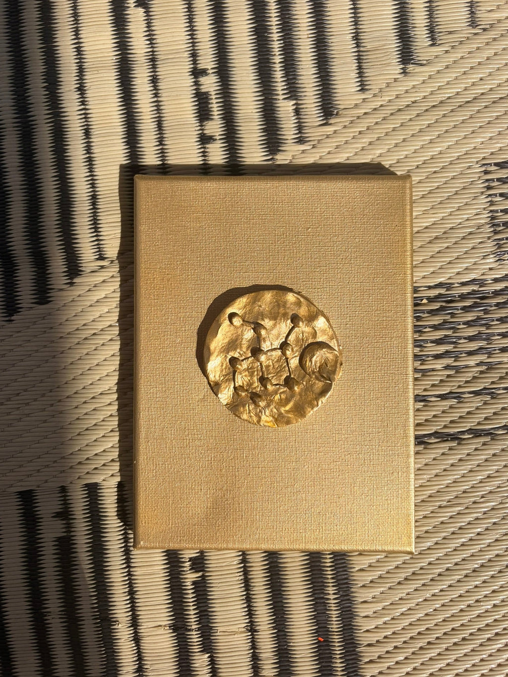 Astra ceramic art on gold canvas, raised metallic gold constellation design against textured background