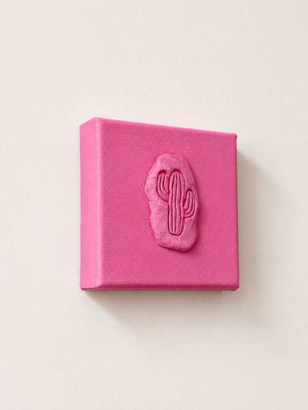Cactus Rosa Grande — a small pink ceramic cactus emblem mounted on a pink box canvas, photographed and held against a plain white background, different angle