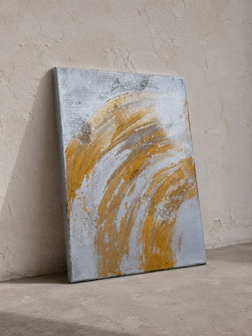 Gold and silver abstract acrylic painting on canvas, sweeping arc brushstrokes, against a wall