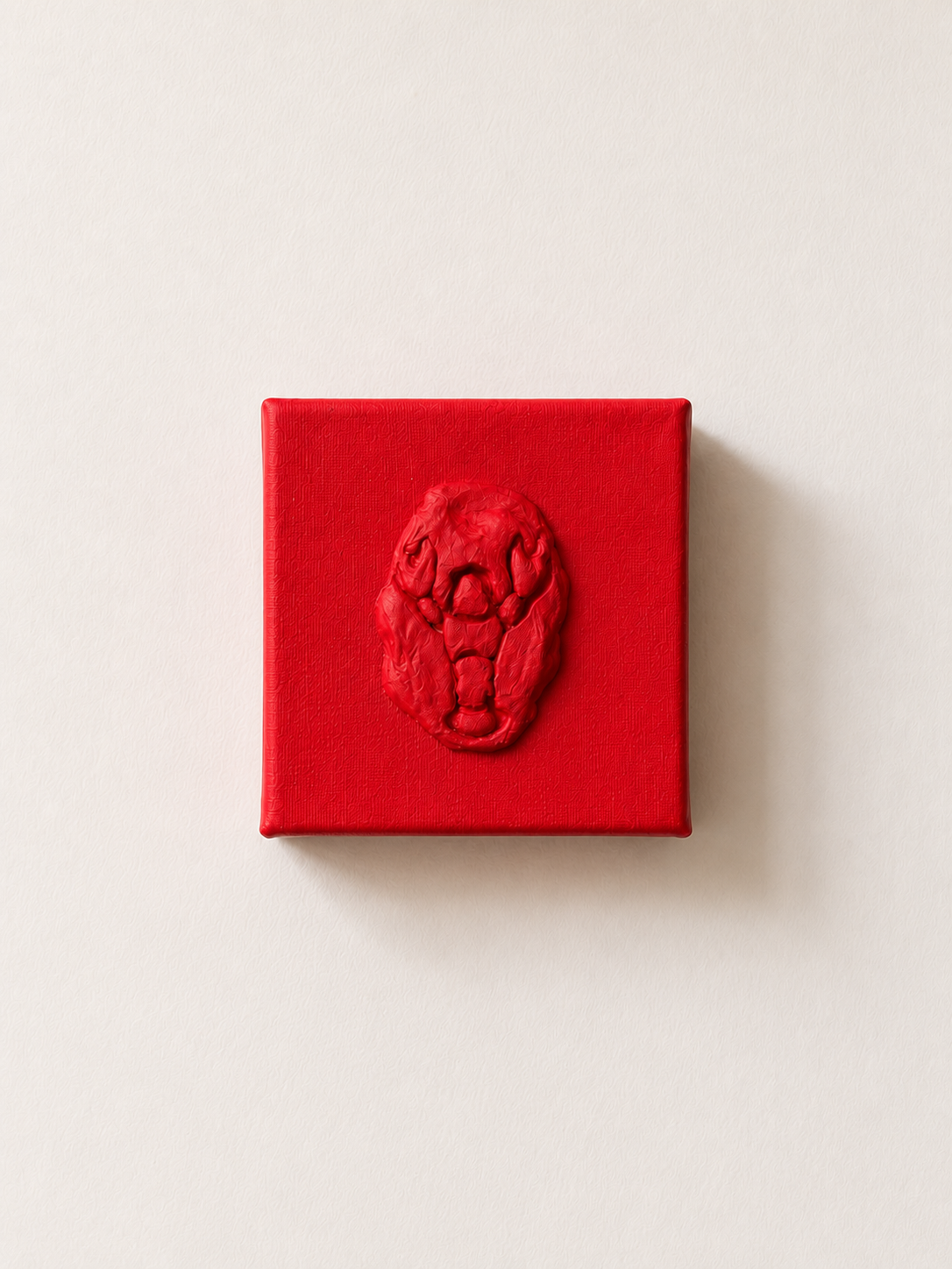 Lobster Rosso Grande — a small red ceramic sacred heart emblem mounted on a red box canvas, photographed against a plain white wall