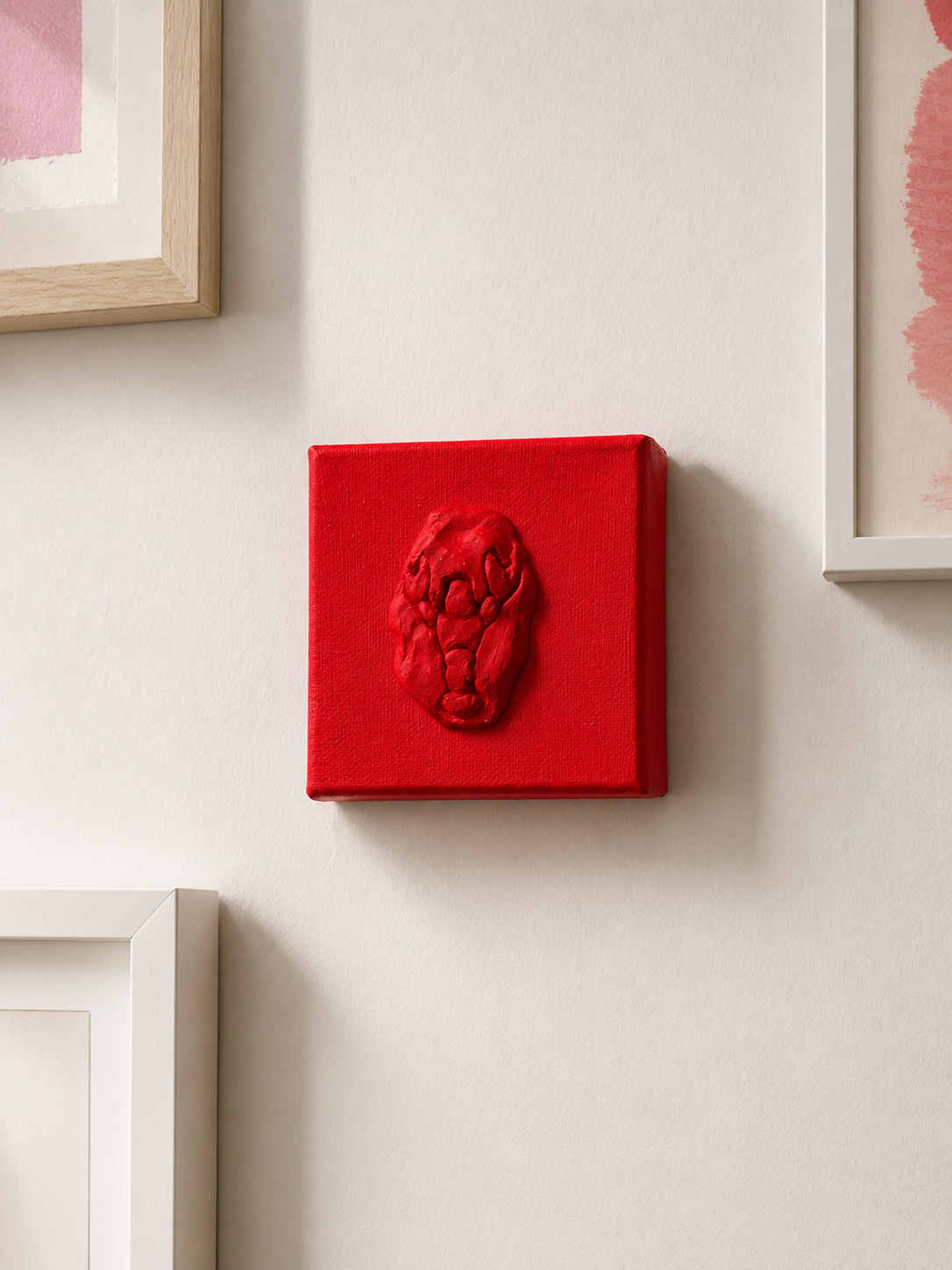 Lobster Rosso Grande — a small red ceramic sacred heart emblem mounted on a red box canvas, photographed on a wall 