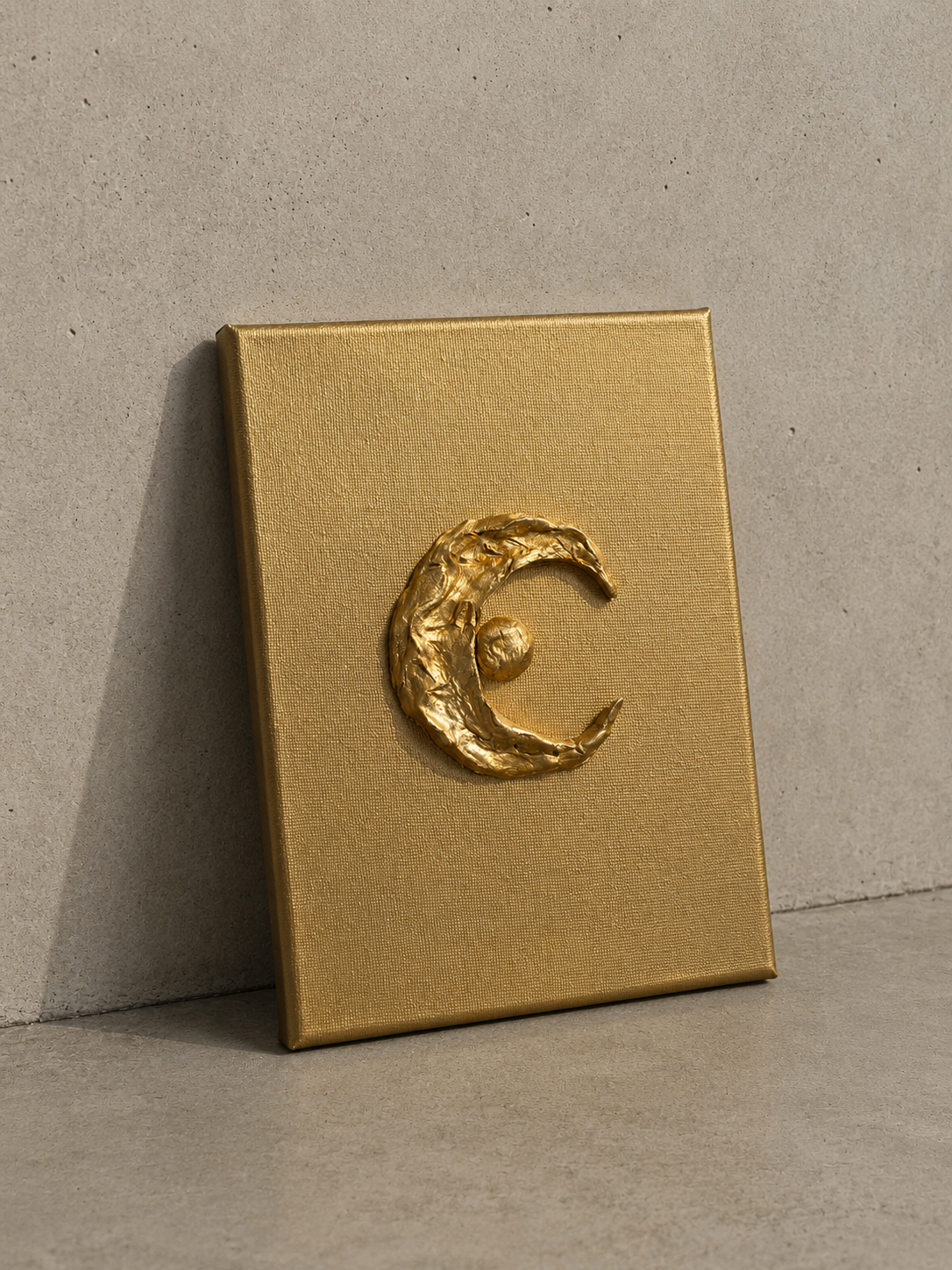 Luna ceramic art on gold canvas, raised metallic gold crescent moon and star design, against a wall