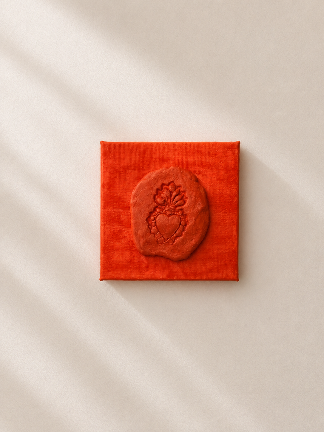 Sacro Cuore Arancia, a small orange ceramic sacred heart emblem mounted on a orange box canvas, photographed against a plain white background.
