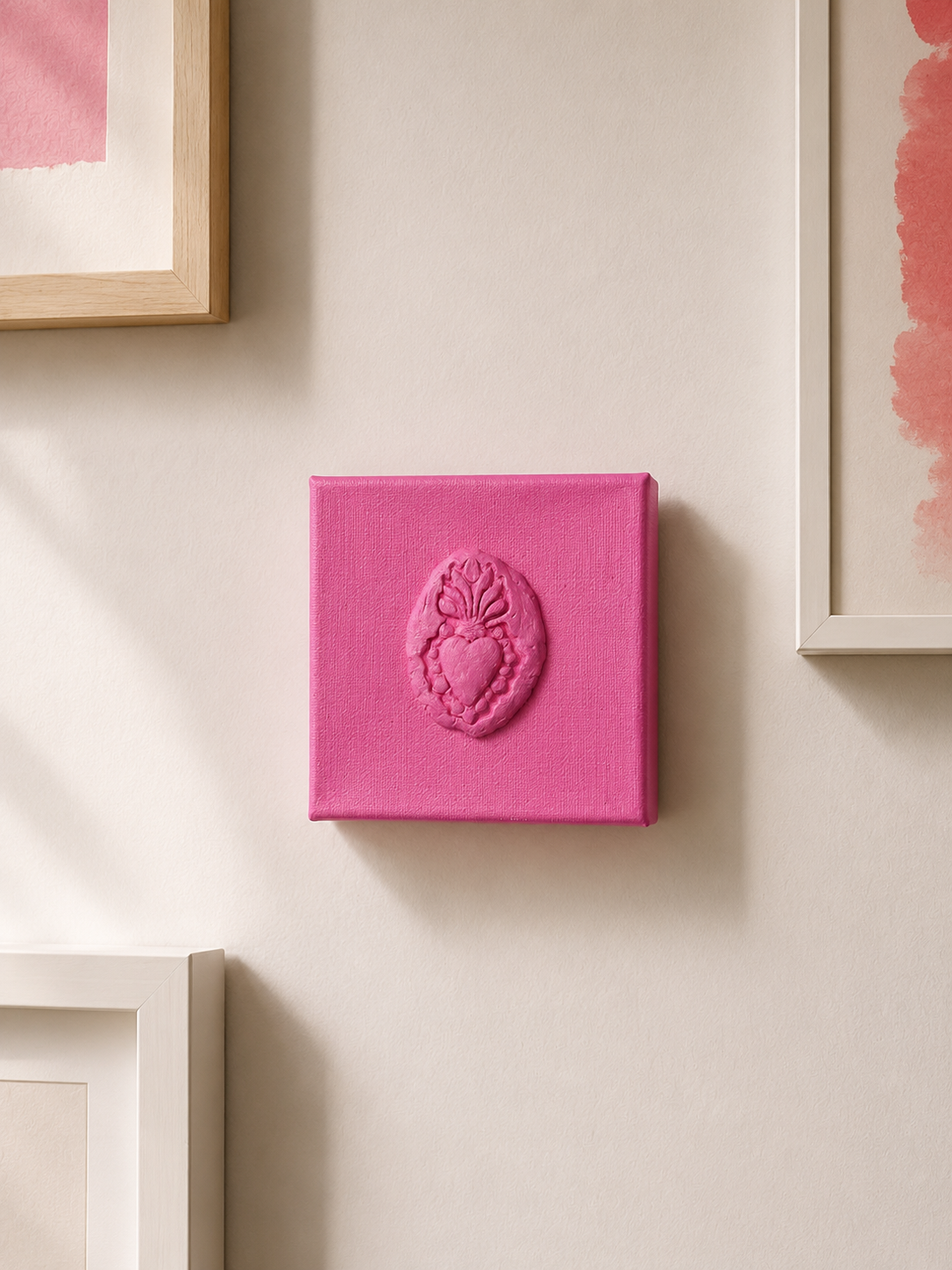 Sacro Cuore Rosa Grande — a small pink ceramic sacred heart emblem mounted on a gallery wall
