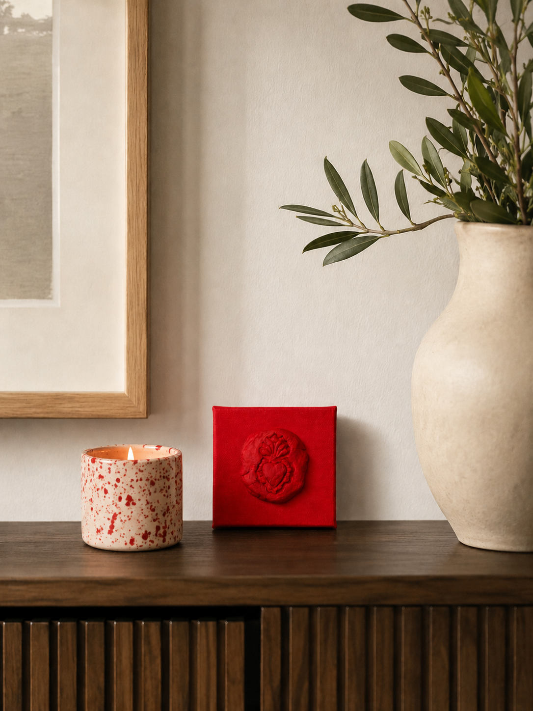 Sacro Cuore Rosso Grande — a small red ceramic sacred heart emblem mounted on a red box canvas, photographed against a console table in a nice home