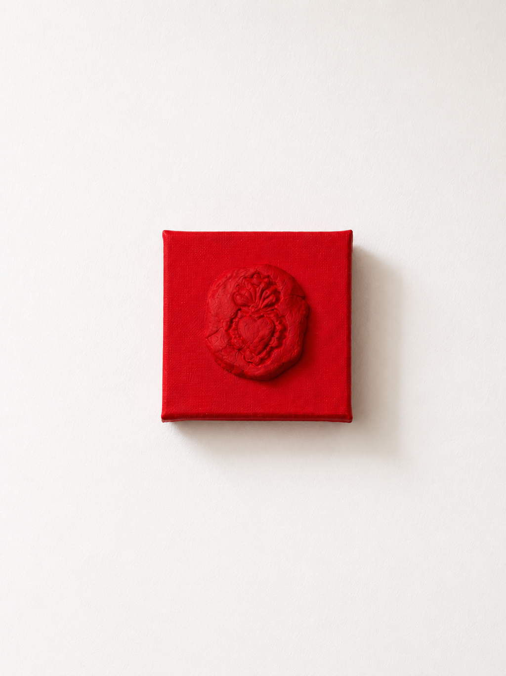 Sacro Cuore Rosso Grande — a small red ceramic sacred heart emblem mounted on a red box canvas, photographed against a plain white background.