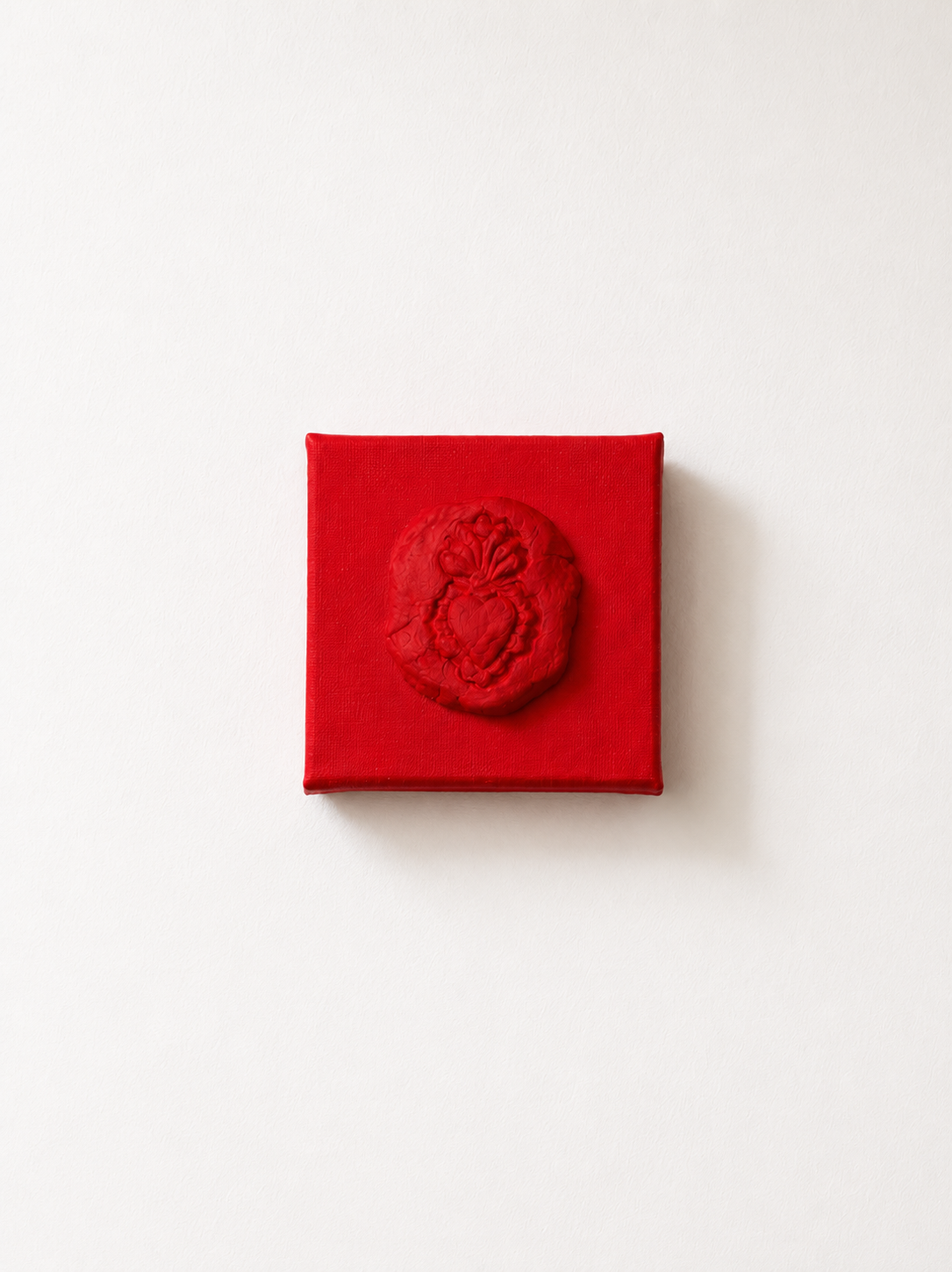 Sacro Cuore Rosso Grande — a small red ceramic sacred heart emblem mounted on a red box canvas, photographed against a plain white background.